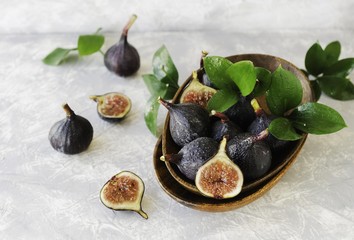 dark blue Fresh figs in a wooden bowl on a white marble table, selective focus