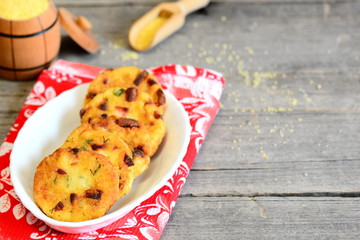 Homemade couscous patties with sausage and greens. Fried couscous patties on a plate and on vintage wooden table with copy space for text. Rustic style 