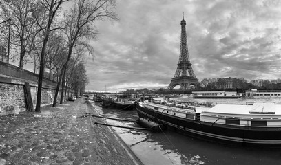 Beautiful panoramic view of the Eiffel Tower and Jena bridge from the river Seine embankment. Dramatic cloudscape. BW photography. Paris, France.