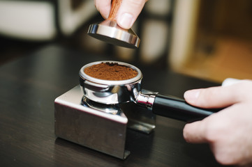 Fototapeta na wymiar man using a tamper to press freshly ground coffee into a tablet