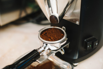 freshly ground coffee beans in a portafilter by the coffee grinder