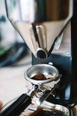 Fototapeta na wymiar freshly ground coffee beans in a portafilter by the coffee grinder