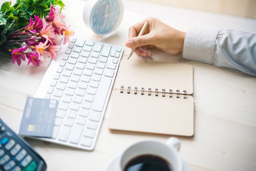 women writing and key board coffee on wooden table