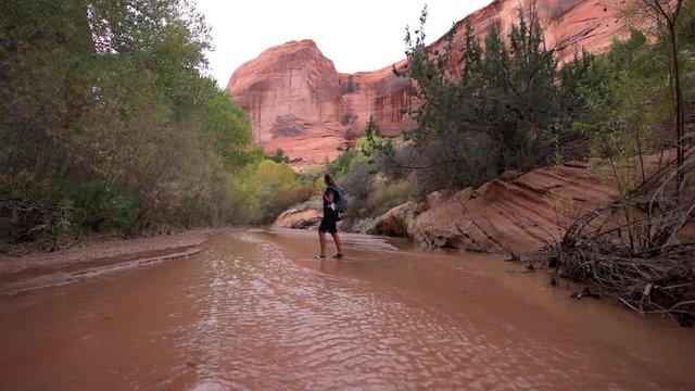 Backpacker crossing small stream Coyote Gulch