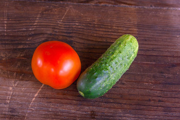 Close up view of fresh, ripe tomatoes and cucumbers on wood background