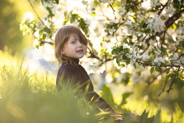 Fototapeta premium Baby girl and spring flowers, childhood emotions