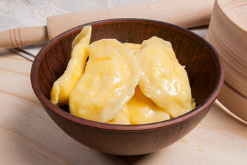 Fresh boiled varenyky or dumpling with cottage cheese or curd in clay bowl on wooden background.