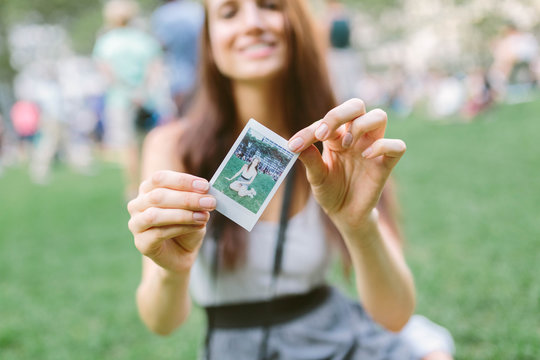 Girl holds instant photo in Bryant Park, Manhattan New York, USA