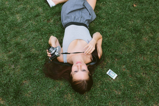 Young Girl Lying on the Grass Taking Pictures With a Vintage Camera