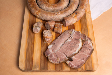 Close up view of sliced roasted traditional homemade sausage with spices and herbs and baked pork with herbs on wooden board.