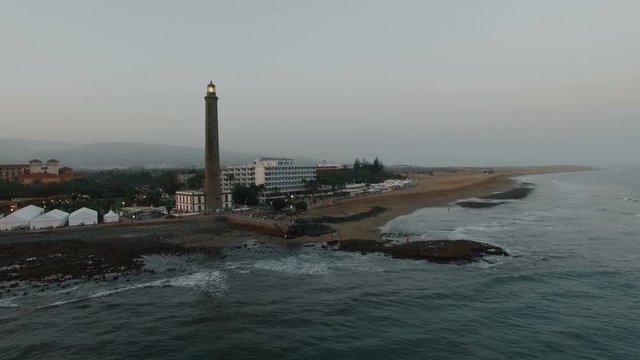 Aerial - Maspalomas Lighthouse and resort area with people on the coast of Gran Canaria. Evening scene
