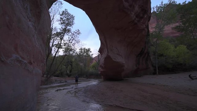 Backpacker walking under Coyote Natural Bridge Glen Canyon National Recreation Area