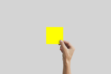 Right hand holding yellow square paper in the right hand. Leaflet presentation