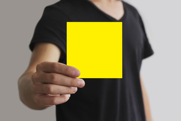 Man showing blank yellow square flyer brochure booklet. Leaflet presentation. Pamphlet hold hands....