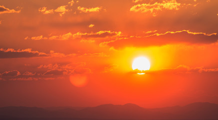 Fototapeta premium Dramatic sunset sky with orange colored clouds and sun.
