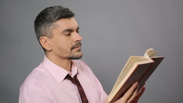 Literary critic sitting at library, reading dry book and yawning, boring novel