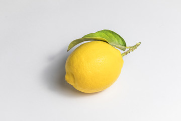 Whole lemon with a leaf on a white background