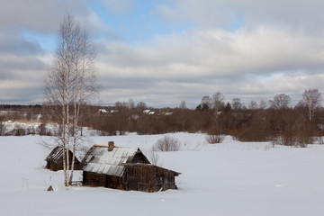 Landscape of old abandoned farm house covered with snow in a frosty winter.
