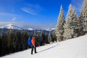Hiker in winter mountains. Man with backpack trekking in mountains. Winter hiking