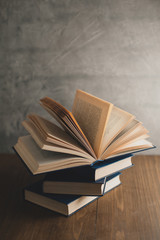 stack of books on a wooden table and on gray concrete wall background