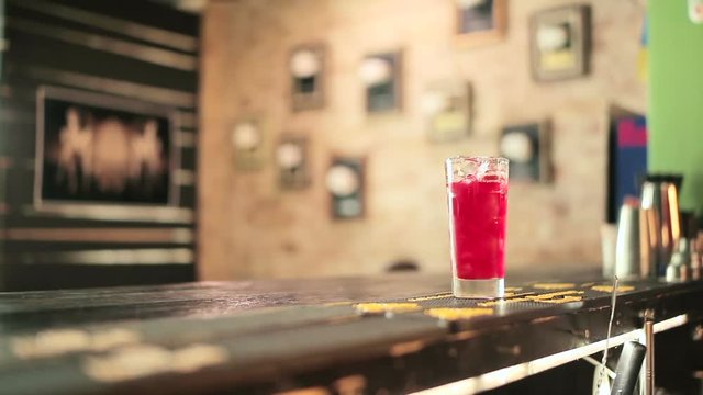 Bartender holding stainer over a glass of drink.