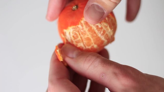 Peeling a tangerine on a white background