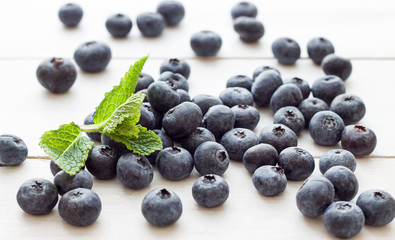 Blueberries with leaves of mint on the white wooden table. Side view