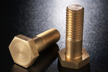 Brass bolts on a dark surface. .