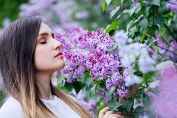 Fototapeta premium Beautiful young woman smelling a lilac