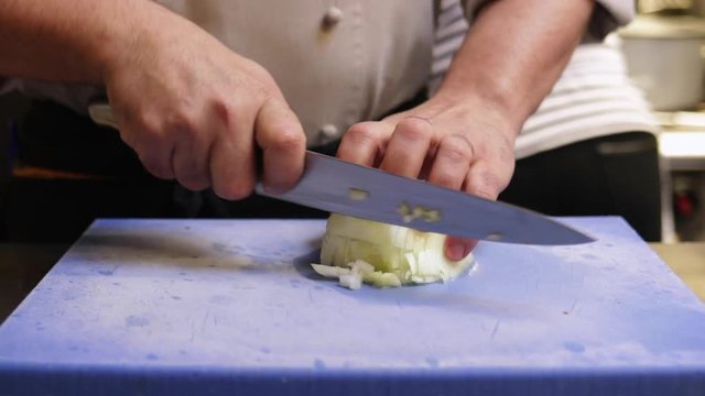 Professional chef chopping onions in a kitchen. Slow motion.