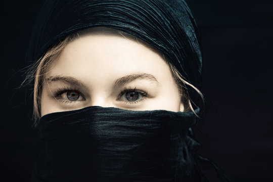 une jeune femme blonde avec un foulard noir sur la tête et le visage