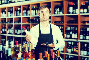 Man seller wearing uniform having bottle of wine