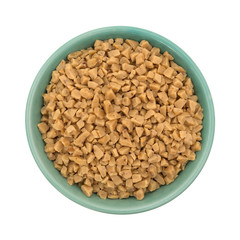 Top view of toffee bits in a green bowl isolated on a white background.
