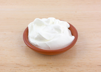 Sour cream in a small bowl on a wood table.