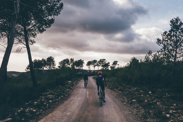 Two cyclist riding on gravel road into the sunset