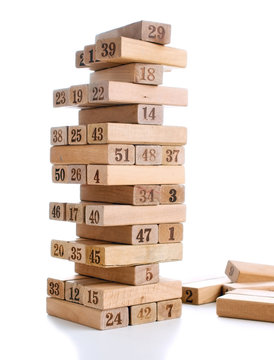 Blocks of game jenga isolated on white background. Vertical tower whole and in game. Wooden blocks in stack with figures digit on body.