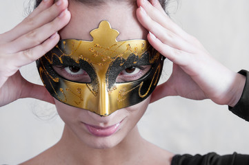 Girl brunette in a theatrical mask holding his hands behind his head and smiles