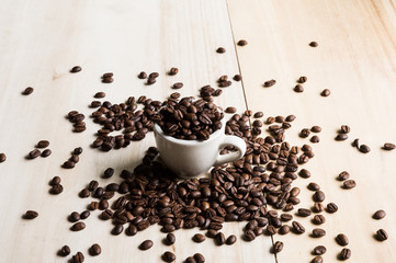 Cup full of coffee beans on wood background