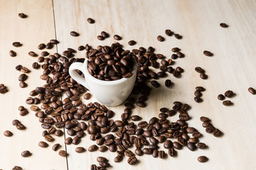 Cup full of coffee beans on wood background