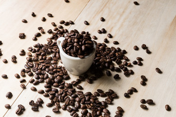 Cup full of coffee beans on wood background