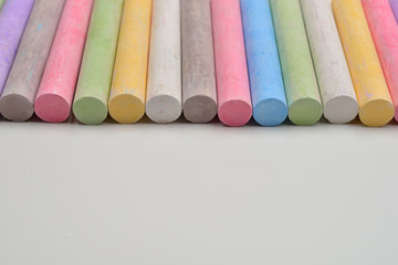 Pieces of chalks in a variety of colors arranged in line on a white background. Back to school,education, arts, creative. Image with room for text