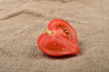 Fresh red tomato cut in half on jute canvas. Healthy nutrition