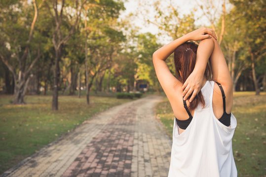 Young female stretching before fitness training session at the park. Healthy young woman warming up outdoors. She is stretching her arms and looking away,hi key. Vintage effect style pictures.