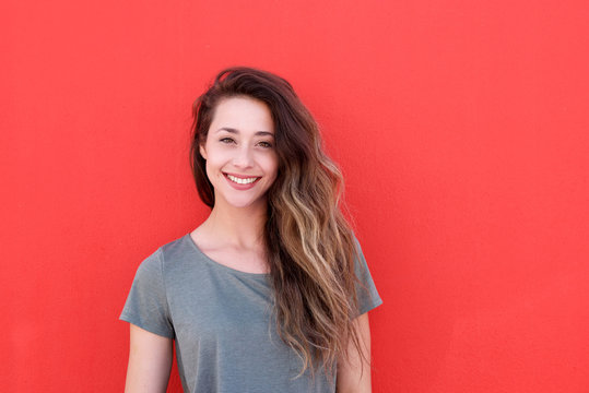 happy young woman standing against red background