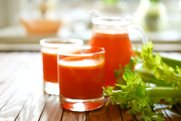 Fresh carrot juice poured into glasses and green celery