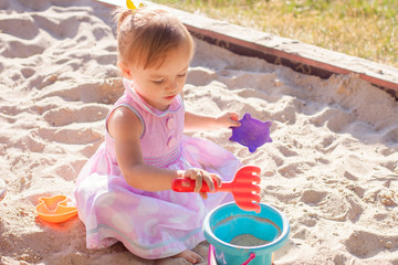 Little girl playing with sand in a sandbox