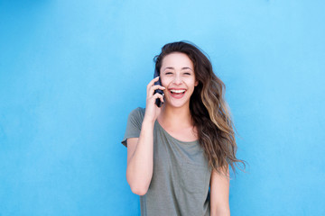 laughing woman talking on cellphone against blue background