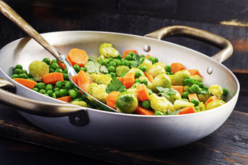 brussels sprouts with green peas cavoulflower in a pan on a old black board.