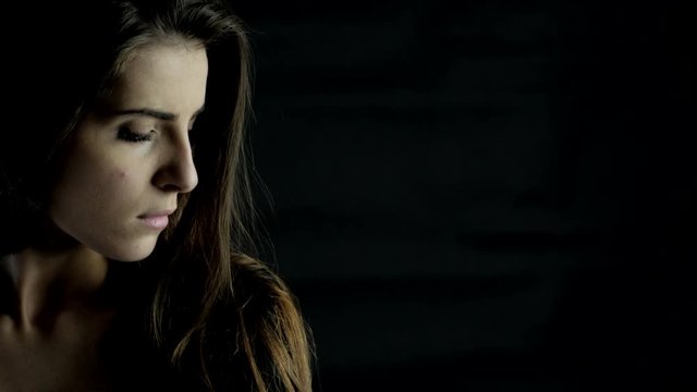 Serious beautiful woman with black background looking camera sad