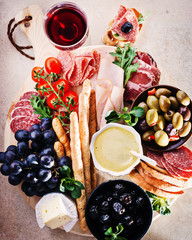 Mediterranean variety food ingredients  with ham, salami, baked olives, bread sticks,brie,tomatoes  for snacks served on a wooden board 